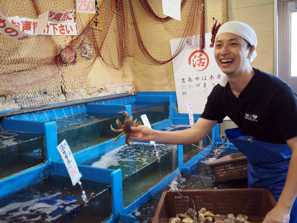 いけすのカニをつかむ様子